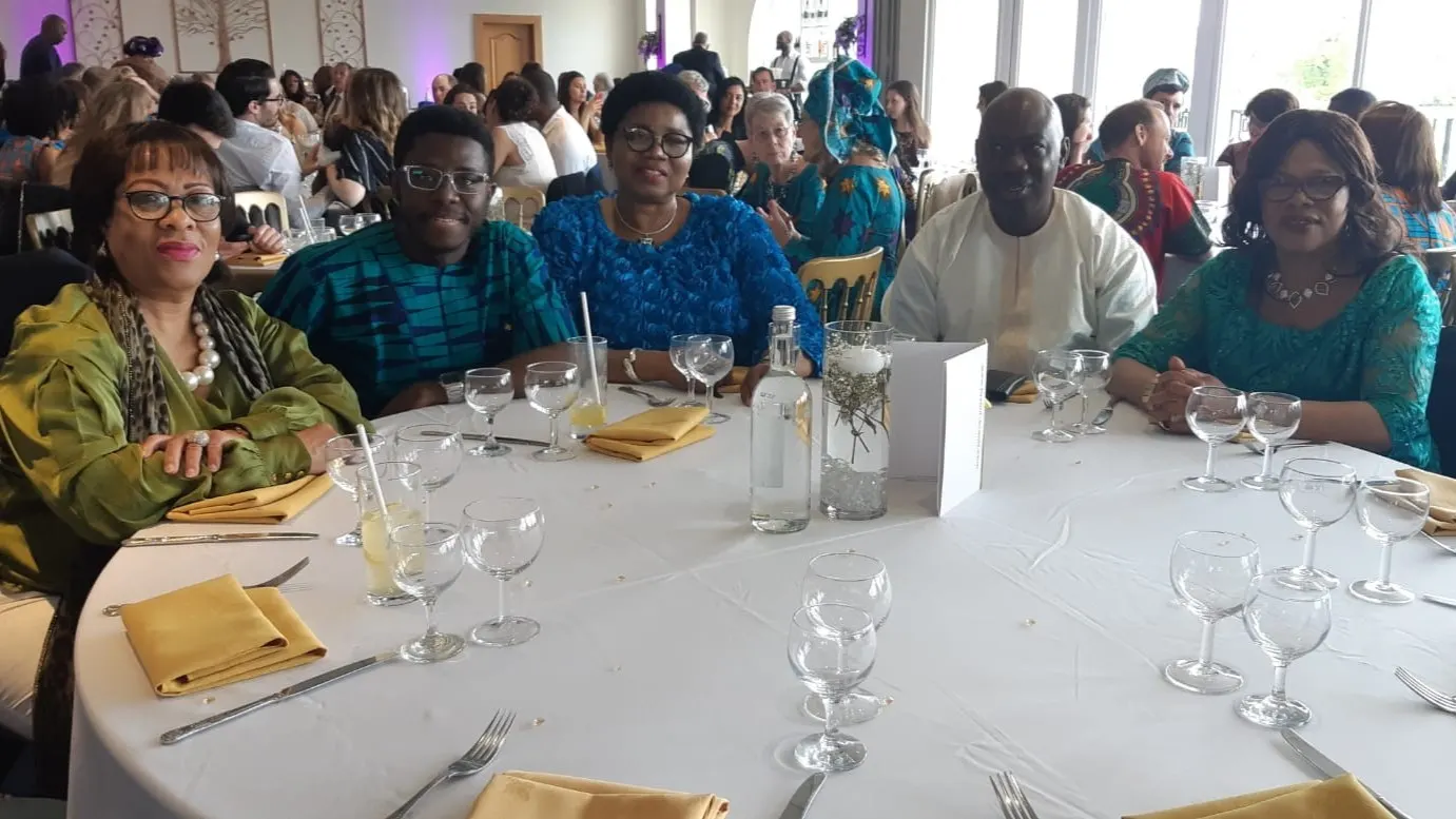 Five AFSF supporters and guests in African formal attire seated at a round dinner table, smiling for a photo.